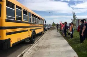 Parents wave to students after their first ride alone on the school bus Aug. 22, 2017. (Jessie Anton/980 CJME)