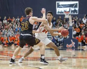 Evan Thomas looks to pass from the top of the key.