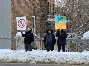 Protesters hold signs that say no to bill 23 and 'hands off' 