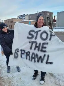 One protester wears a poncho that says 'stop the sprawl'