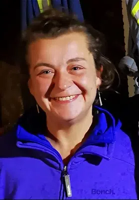 Sarah Foord smiling, wearing a purple Bench zip up sweater, long earings and hair pulled back