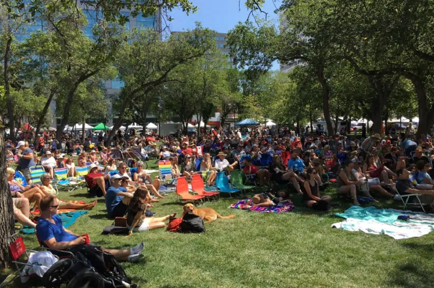 Una grande folla di persone sedute sull'erba durante un evento all'aperto.